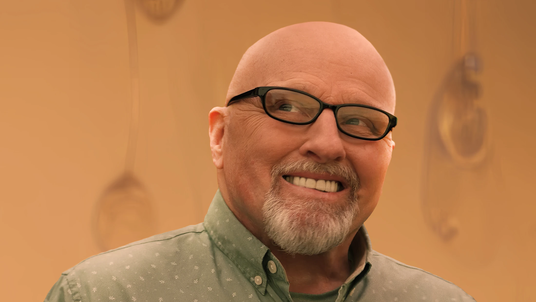 Mickey, an older man with polycythemia vera, smiles in front of a tan-colored, AI-generated backdrop of glass water droplets.